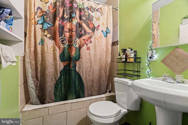 bathroom with shower / bath combination with curtain, toilet, and a sink