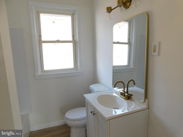 half bath with baseboards, toilet, wood finished floors, and vanity