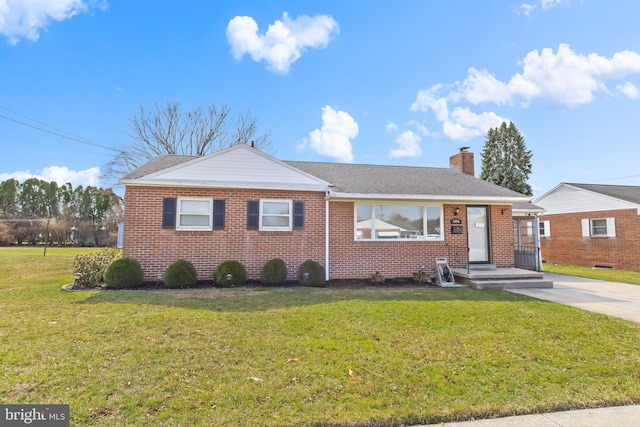 ranch-style home with brick siding, a chimney, and a front lawn