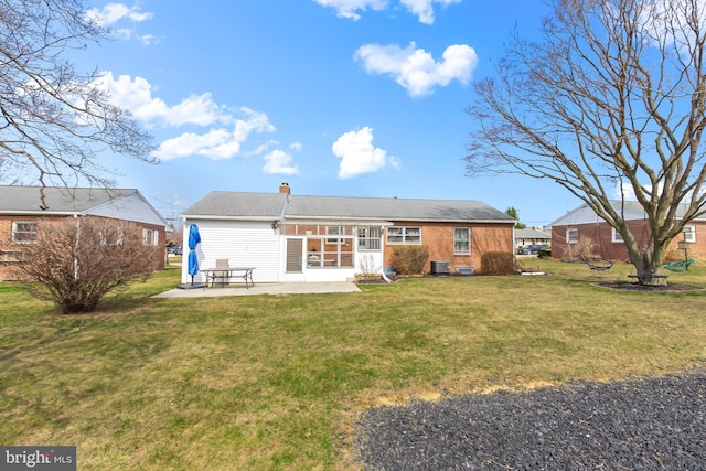 back of house with a patio, cooling unit, a chimney, a lawn, and brick siding