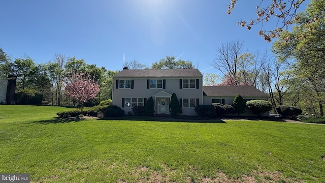 colonial house featuring a front lawn and a chimney