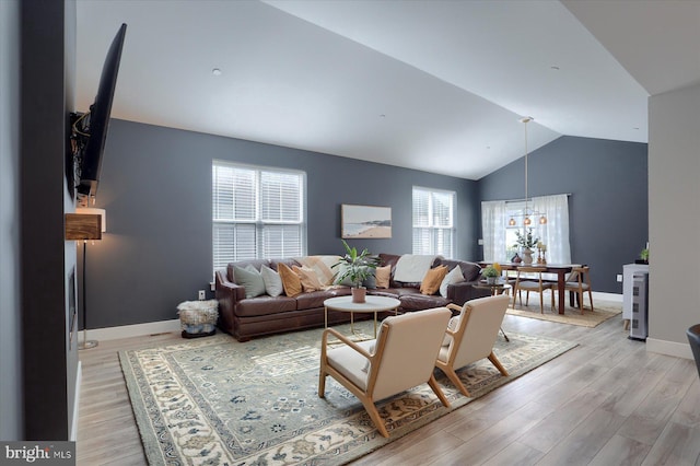 living room with lofted ceiling, baseboards, and light wood finished floors