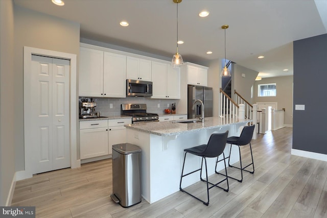 kitchen with tasteful backsplash, light wood finished floors, stainless steel appliances, and a sink