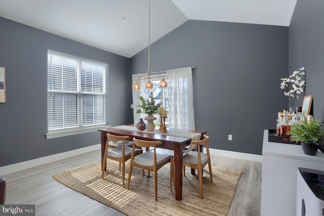 dining space featuring baseboards, light wood-style floors, and lofted ceiling