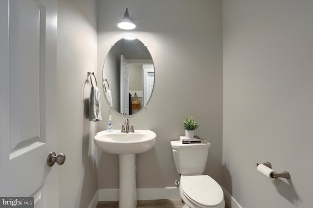 bathroom featuring a sink, baseboards, and toilet