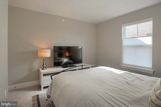 bedroom with light colored carpet and baseboards