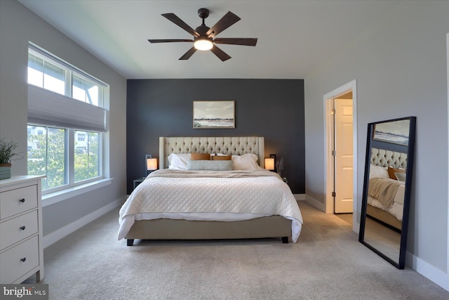 bedroom featuring baseboards, light colored carpet, ceiling fan, and an accent wall