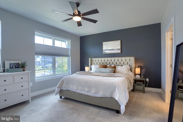 bedroom featuring light colored carpet, a ceiling fan, and baseboards