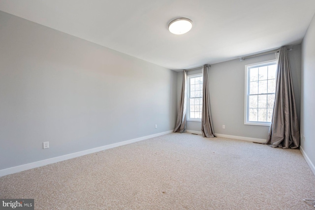 spare room with baseboards and light carpet