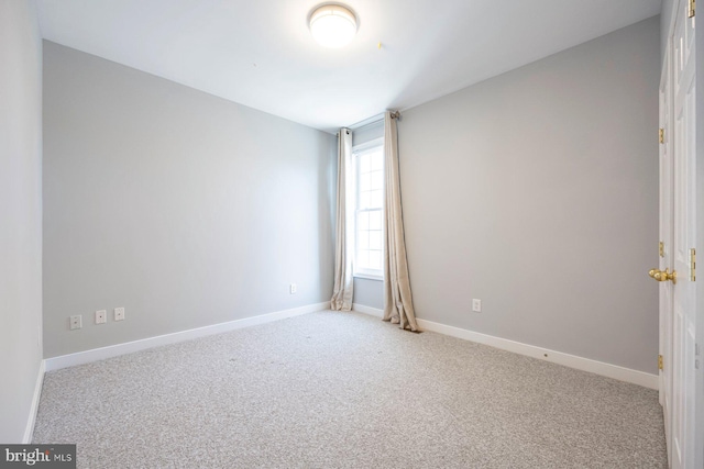 empty room featuring carpet and baseboards