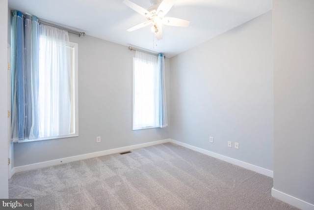 carpeted spare room with a ceiling fan, baseboards, and visible vents