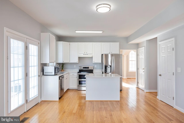 kitchen with light wood-type flooring, visible vents, under cabinet range hood, stainless steel appliances, and light countertops