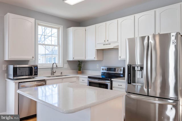 kitchen with under cabinet range hood, stainless steel appliances, white cabinets, and a sink