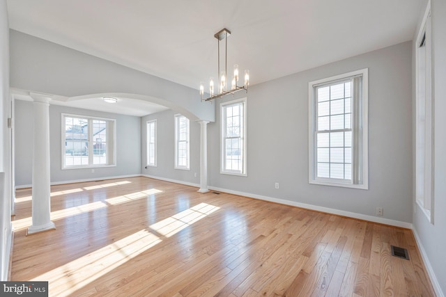 interior space featuring visible vents, light wood-style flooring, baseboards, and decorative columns