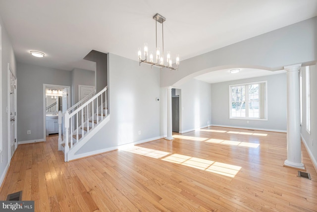 interior space featuring visible vents, baseboards, stairway, light wood-type flooring, and decorative columns