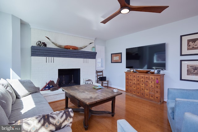 living area featuring ceiling fan, baseboards, wood finished floors, and a fireplace