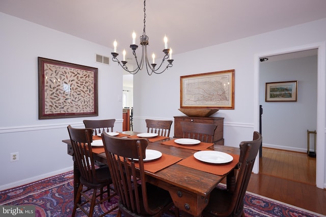 dining area featuring hardwood / wood-style flooring, a notable chandelier, baseboards, and visible vents