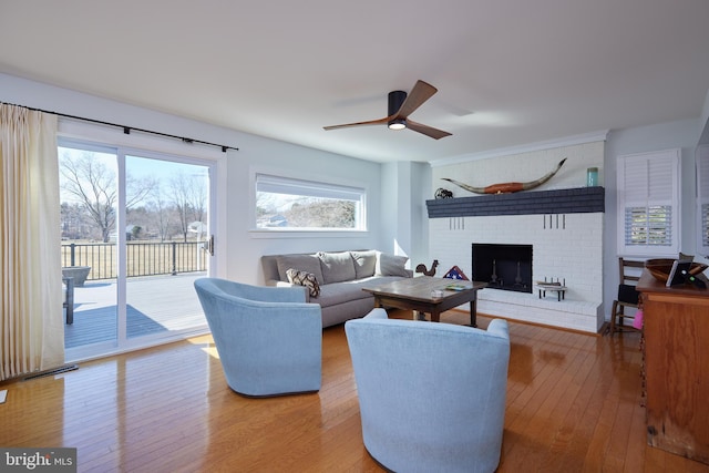 living room featuring a brick fireplace, a ceiling fan, and wood-type flooring