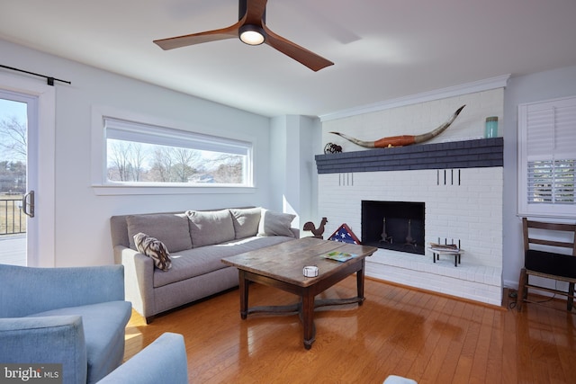 living room featuring a brick fireplace, a ceiling fan, and wood finished floors