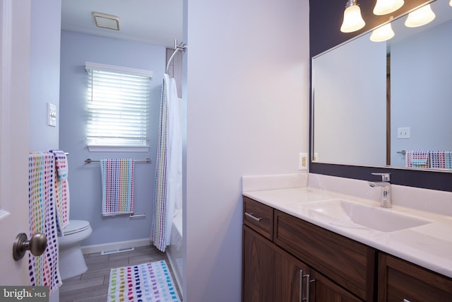 full bath featuring toilet, shower / tub combo with curtain, wood finished floors, baseboards, and vanity