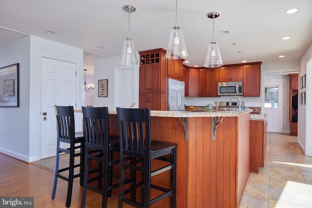 kitchen with pendant lighting, recessed lighting, stainless steel appliances, a breakfast bar area, and baseboards