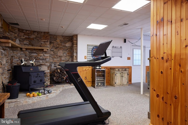 exercise area with a wood stove, carpet, visible vents, and wine cooler