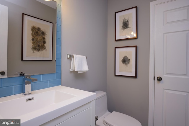 half bathroom featuring tasteful backsplash, toilet, and vanity