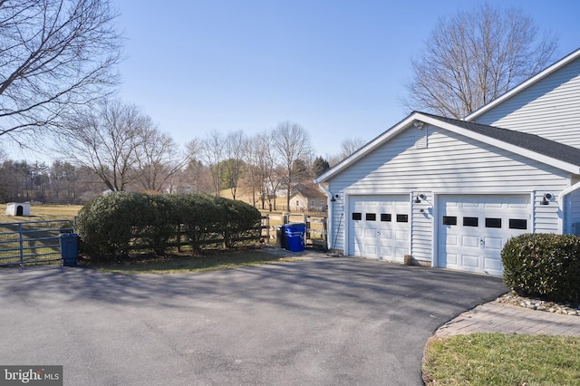 view of home's exterior with an attached garage, driveway, and fence