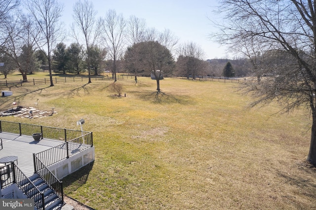 view of yard featuring a rural view, fence, and a wooden deck