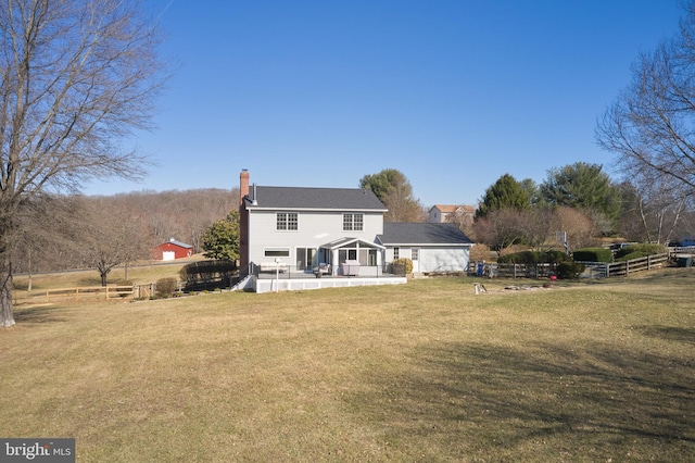 rear view of property with fence, a lawn, and a chimney