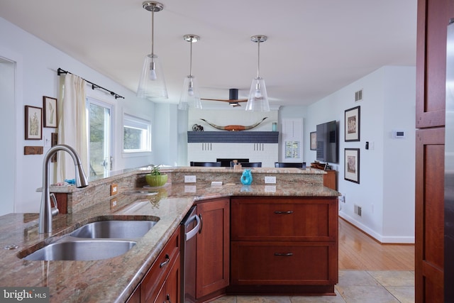 kitchen with decorative light fixtures, open floor plan, stone countertops, and a sink