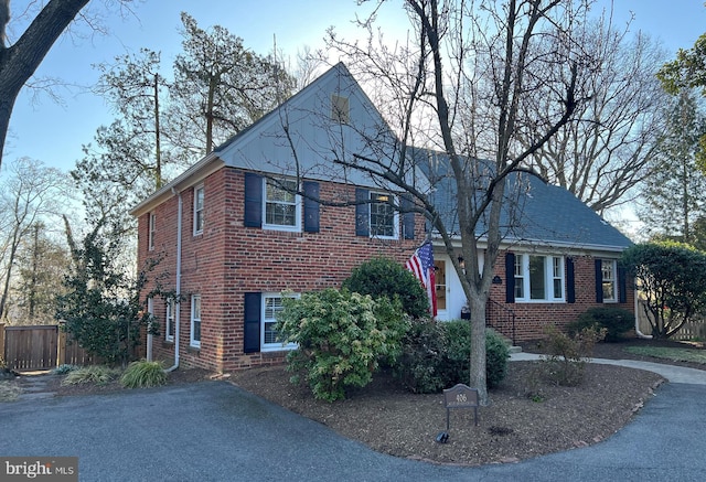 view of front of home with aphalt driveway, brick siding, and fence