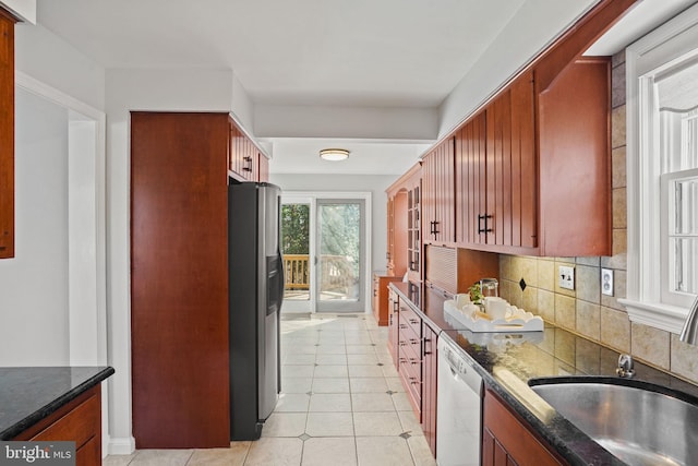 kitchen with tasteful backsplash, dark stone countertops, stainless steel appliances, and a sink