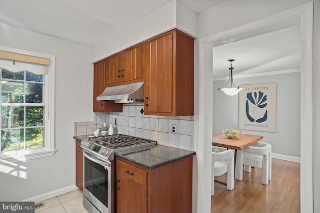 kitchen featuring brown cabinetry, visible vents, stainless steel gas range, extractor fan, and backsplash