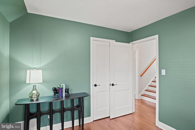 interior space featuring stairway, baseboards, wood finished floors, and vaulted ceiling