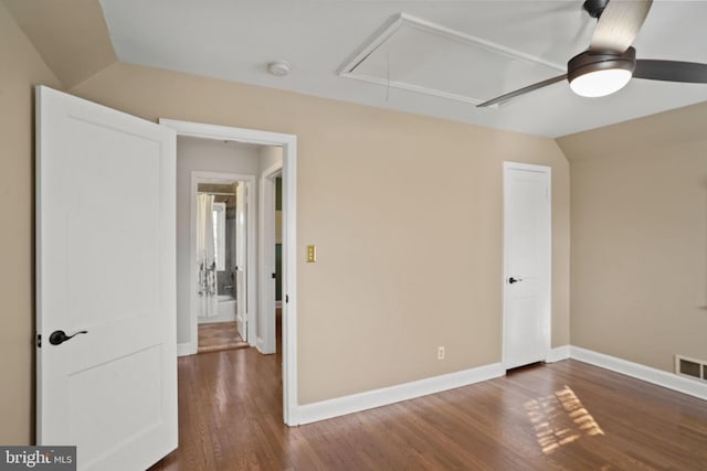 empty room featuring baseboards, lofted ceiling, attic access, and dark wood-style flooring