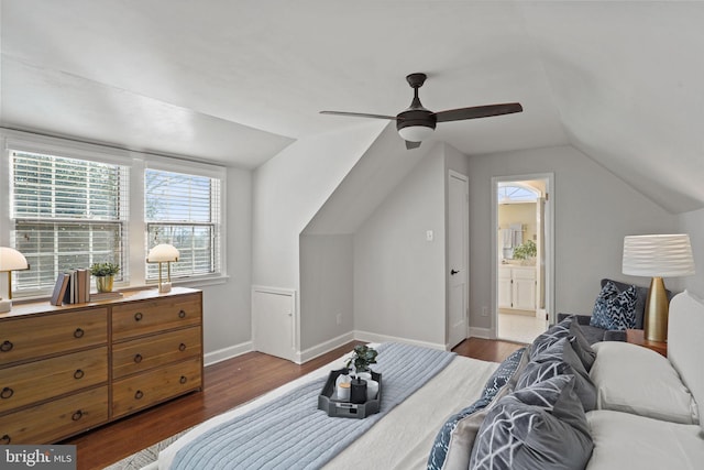 bedroom featuring wood finished floors, baseboards, lofted ceiling, ceiling fan, and connected bathroom