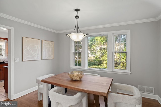 dining space with light wood finished floors, visible vents, baseboards, and ornamental molding