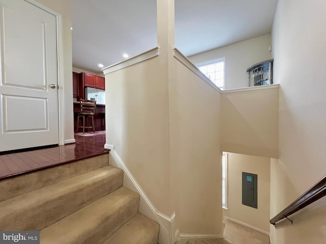 stairway with electric panel, recessed lighting, and baseboards