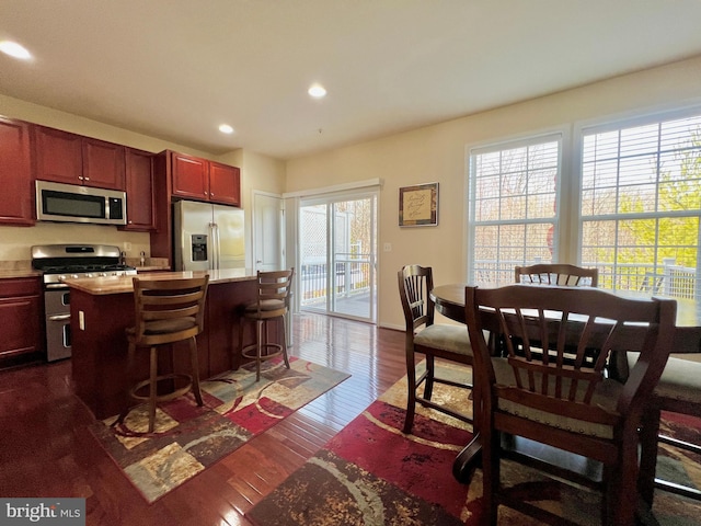 kitchen featuring a kitchen island, appliances with stainless steel finishes, light countertops, dark brown cabinets, and dark wood-style flooring