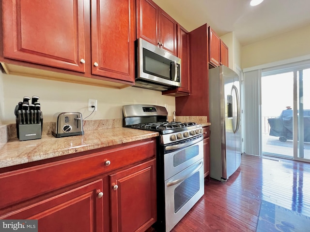 kitchen with light countertops, dark wood-style flooring, reddish brown cabinets, and stainless steel appliances