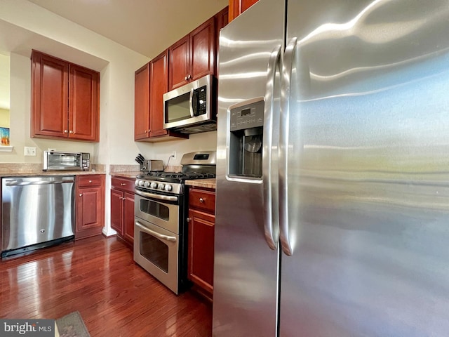 kitchen featuring dark wood-style floors, a toaster, appliances with stainless steel finishes, and light stone countertops