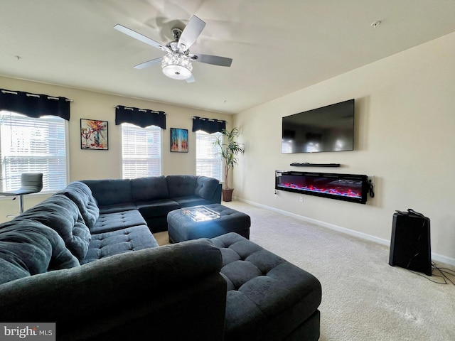 living area with baseboards, carpet, a glass covered fireplace, and a ceiling fan