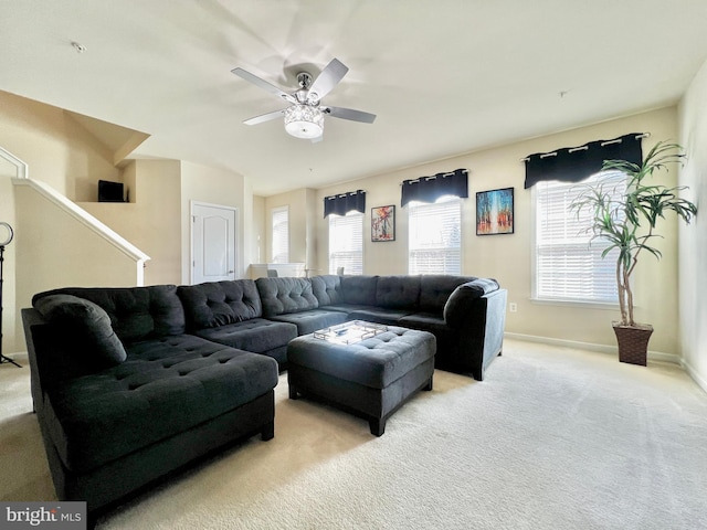 living room with ceiling fan, baseboards, and light carpet