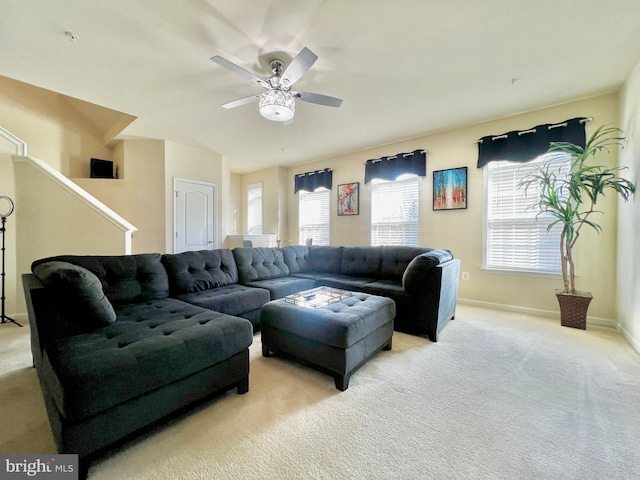 living area with light carpet, baseboards, and a ceiling fan