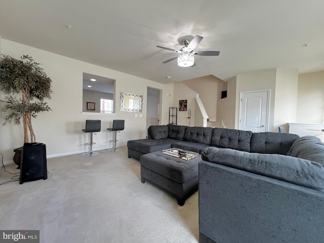 living area featuring stairway, a ceiling fan, baseboards, and light carpet