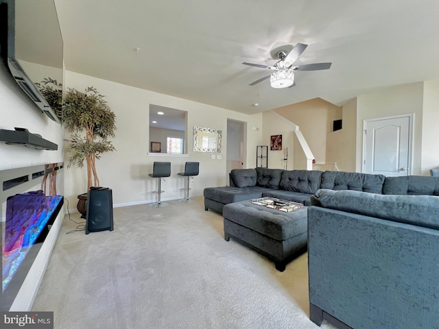 carpeted living room featuring baseboards and a ceiling fan