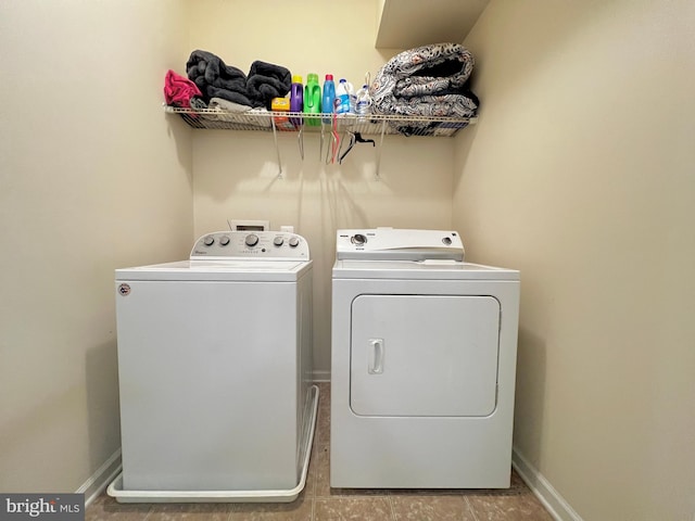 clothes washing area featuring laundry area, baseboards, and washing machine and clothes dryer