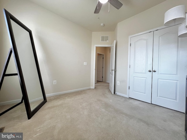 unfurnished bedroom featuring visible vents, a closet, baseboards, light colored carpet, and ceiling fan