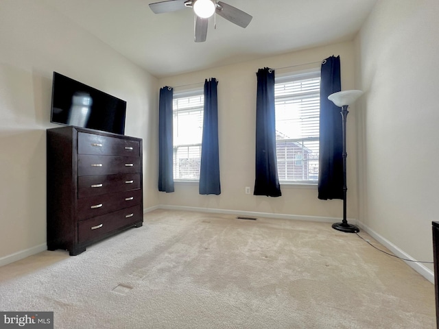 unfurnished bedroom featuring baseboards, multiple windows, carpet, and ceiling fan